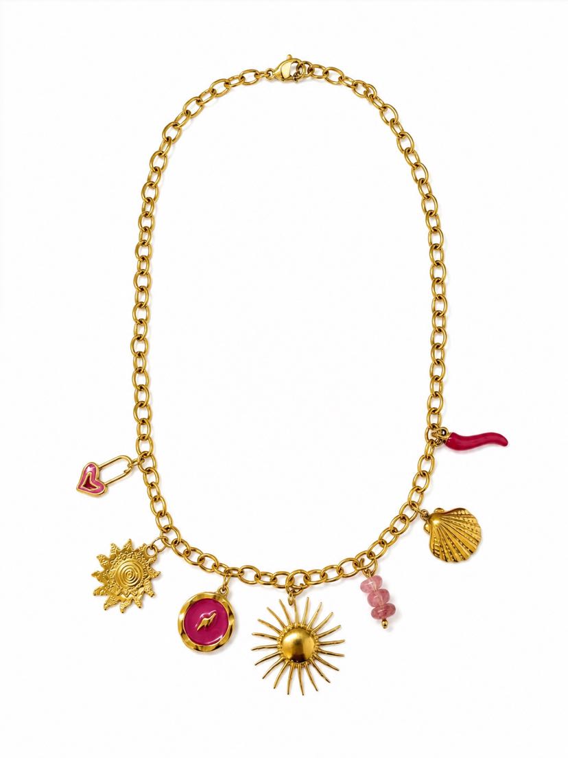 Collier Solina à plat sur fond crème, chaîne forçat d'or et 7 pendentifs : deux soleils rayonnants ciselés, médaillon rond émaillé magenta gravé d'un éclair, cadenas-cœur émaillé rose tendre, perles cylindriques en quartz rose pâle, coquille pèlerine bombée et cornicello rouge émaillé en goutte