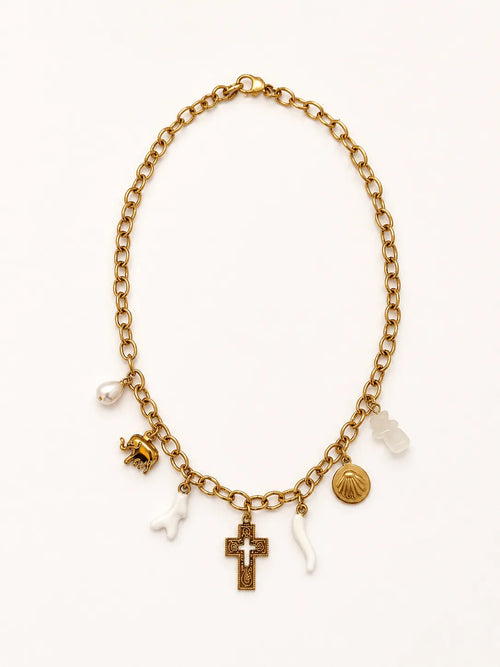 Collier Cétina à plat sur fond blanc, chaîne forçat d'or et 6 pendentifs visibles — éléphant d'or, corail blanc, perle baroque, crucifix byzantin ciselé, coquille pèlerine et corail blanc