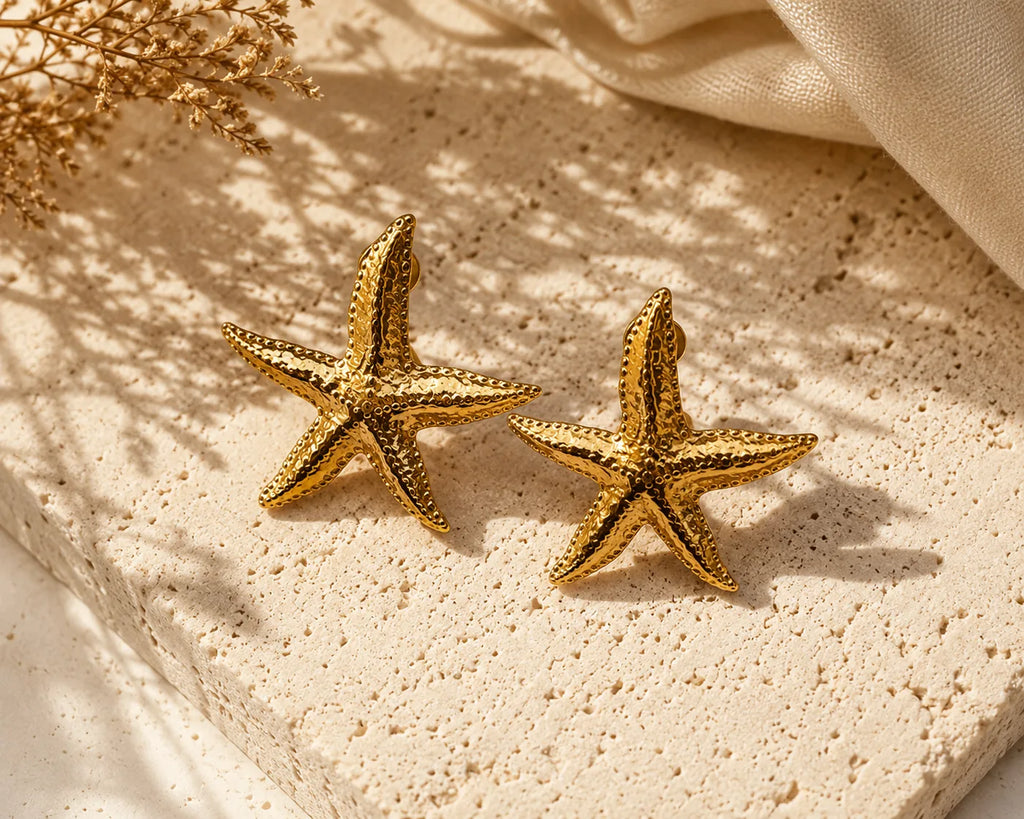 Boucles Sirena étoile de mer posées sur un bloc de travertin crème, ombre de fleurs séchées, drap de lin, esprit d'atelier